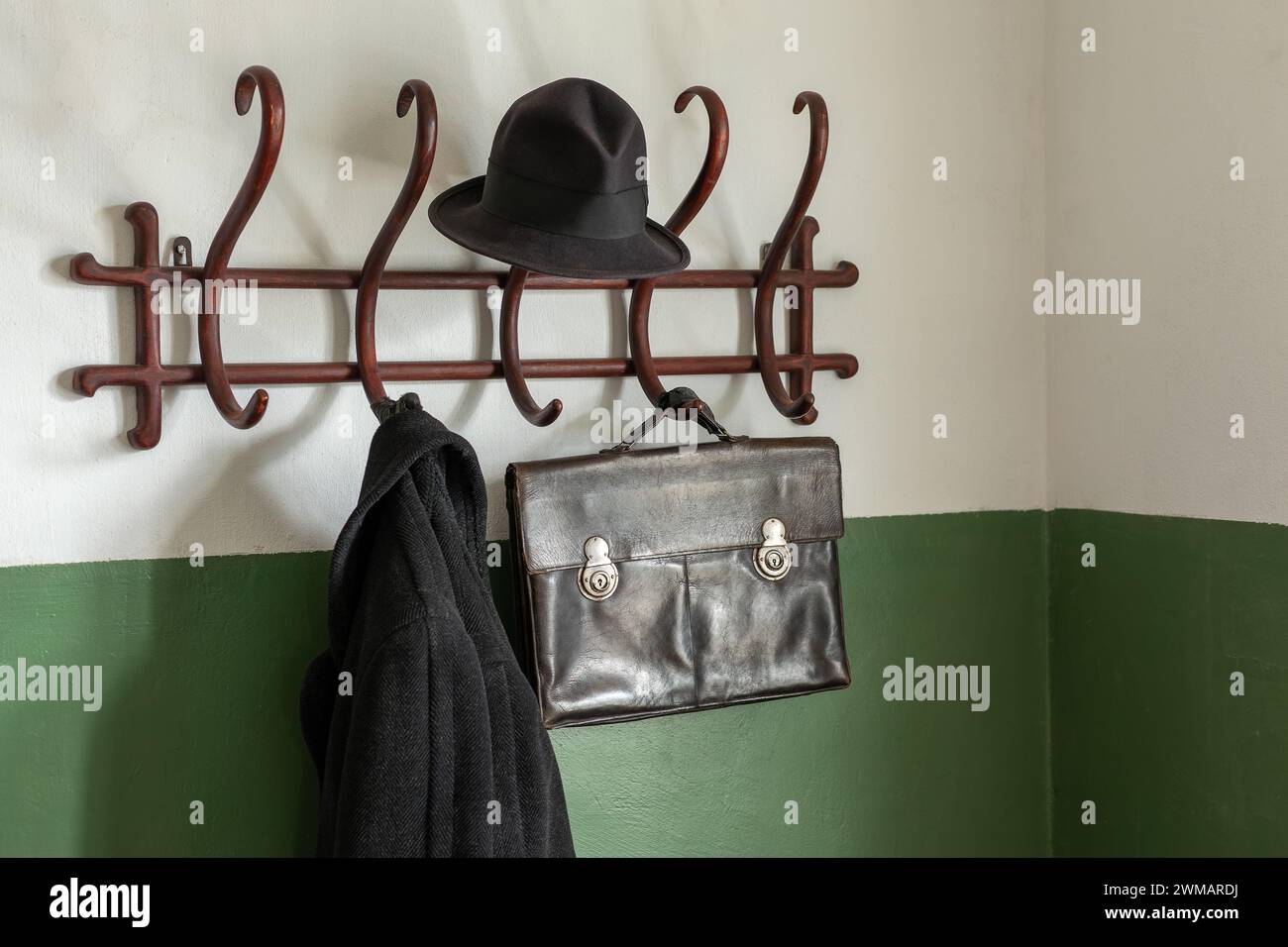 Black ancient leather briefcase, black hat and coat on the vintage wooden cloth hanger. Stock Photo