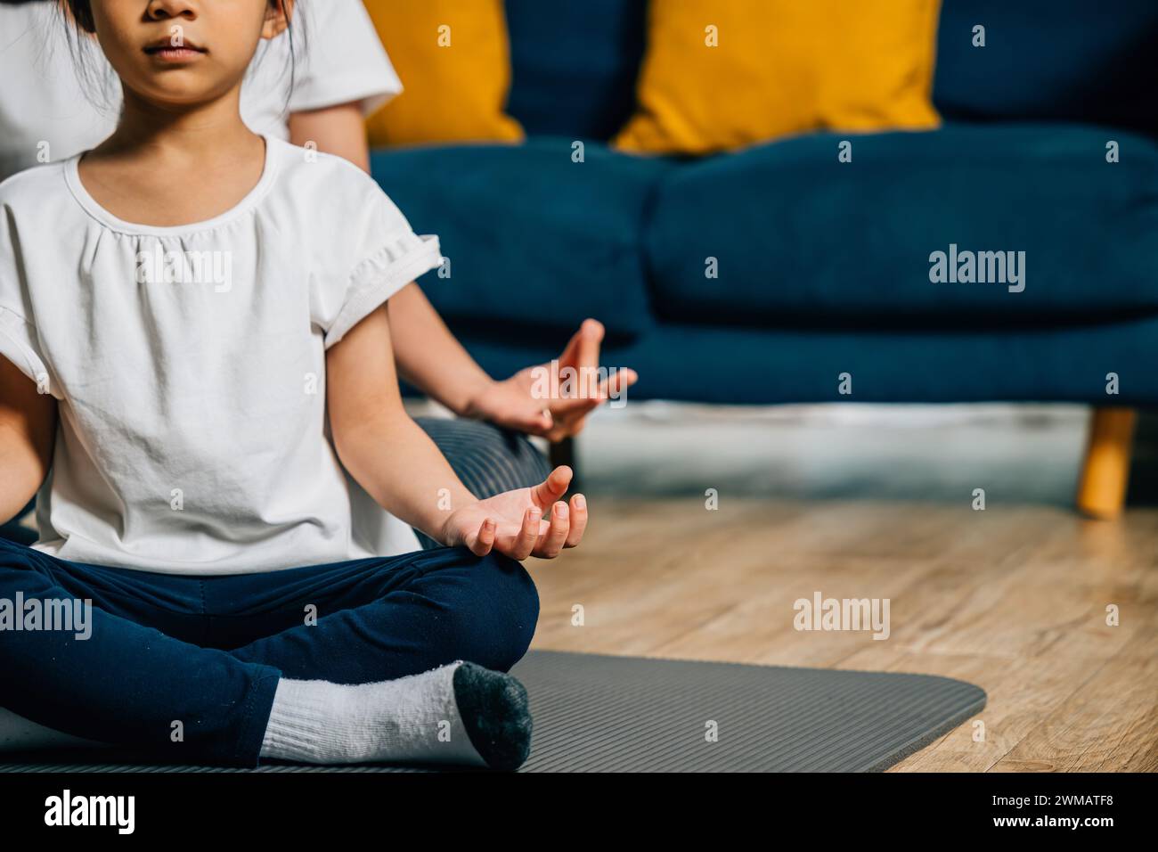 A mother and her daughter find serenity in family yoga sitting in lotus ...