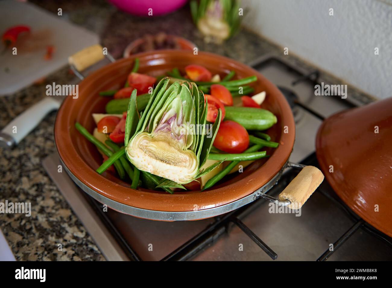 Still life. A half of organic ripe artichoke and veggies in a tagine on