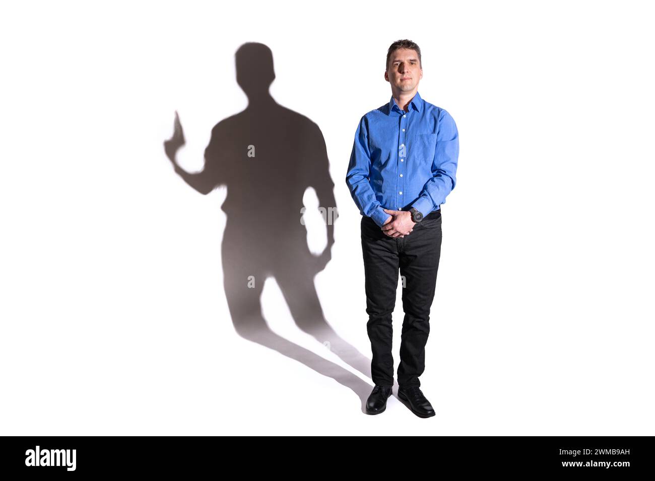 friendly and harmless looking young man whose shadow in the background reveals his evil character Stock Photo