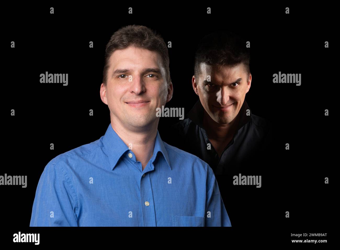Nice looking young man with an evil character, a wicked looking face standing in the shadows behind him Stock Photo