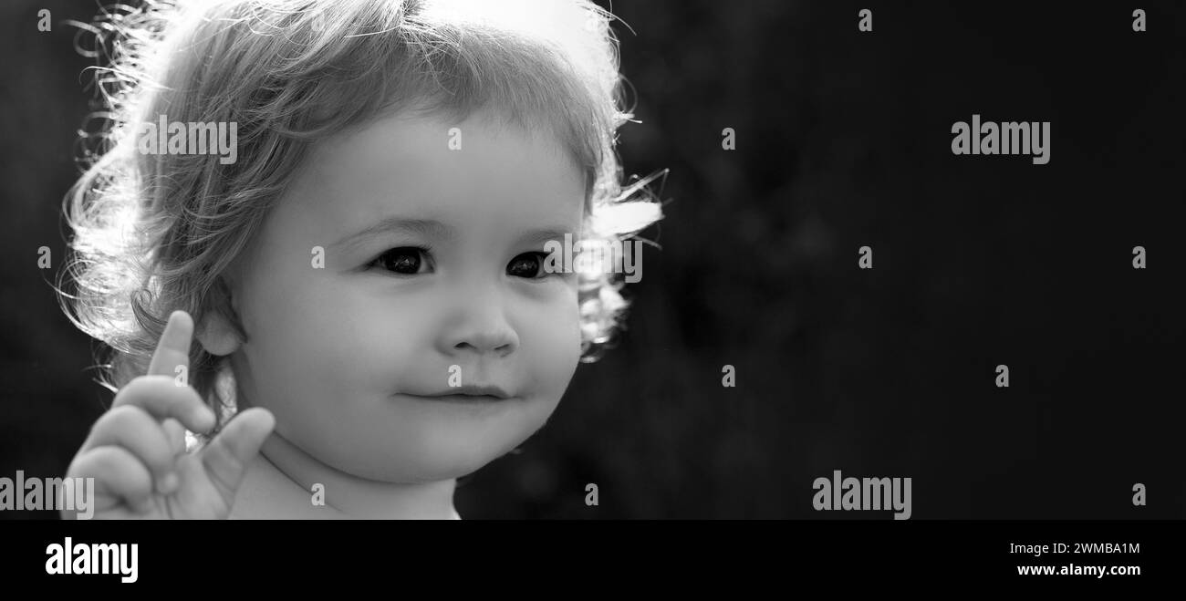 Banner with spring child face. Close up portrait of a cute Baby in green nature park on sunny day. Childhood and parenting concept. Stock Photo