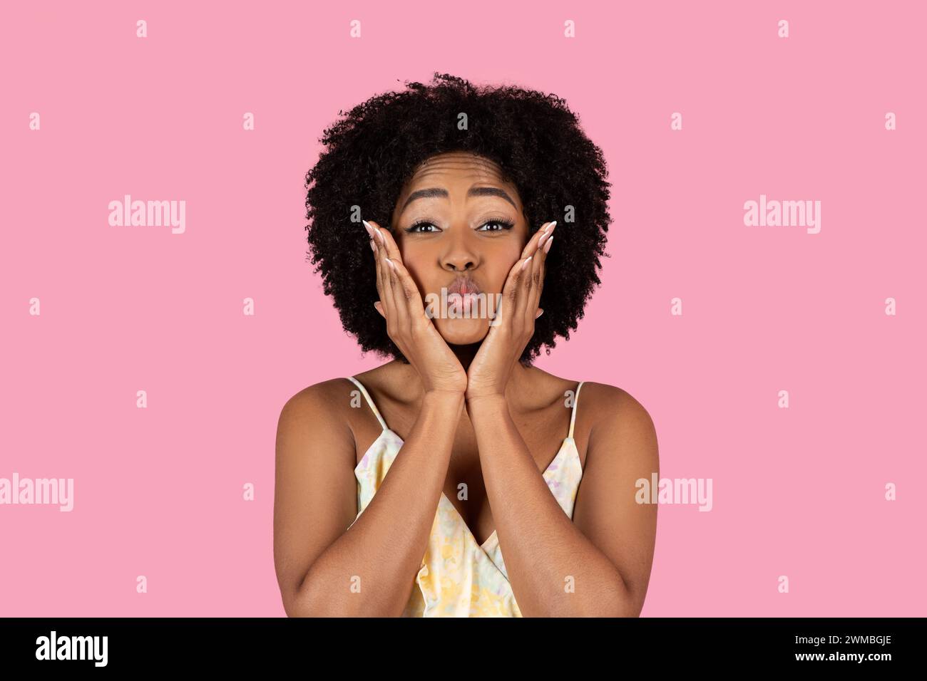 Playful African American woman with curly hair making a funny face with puffed cheeks Stock Photo