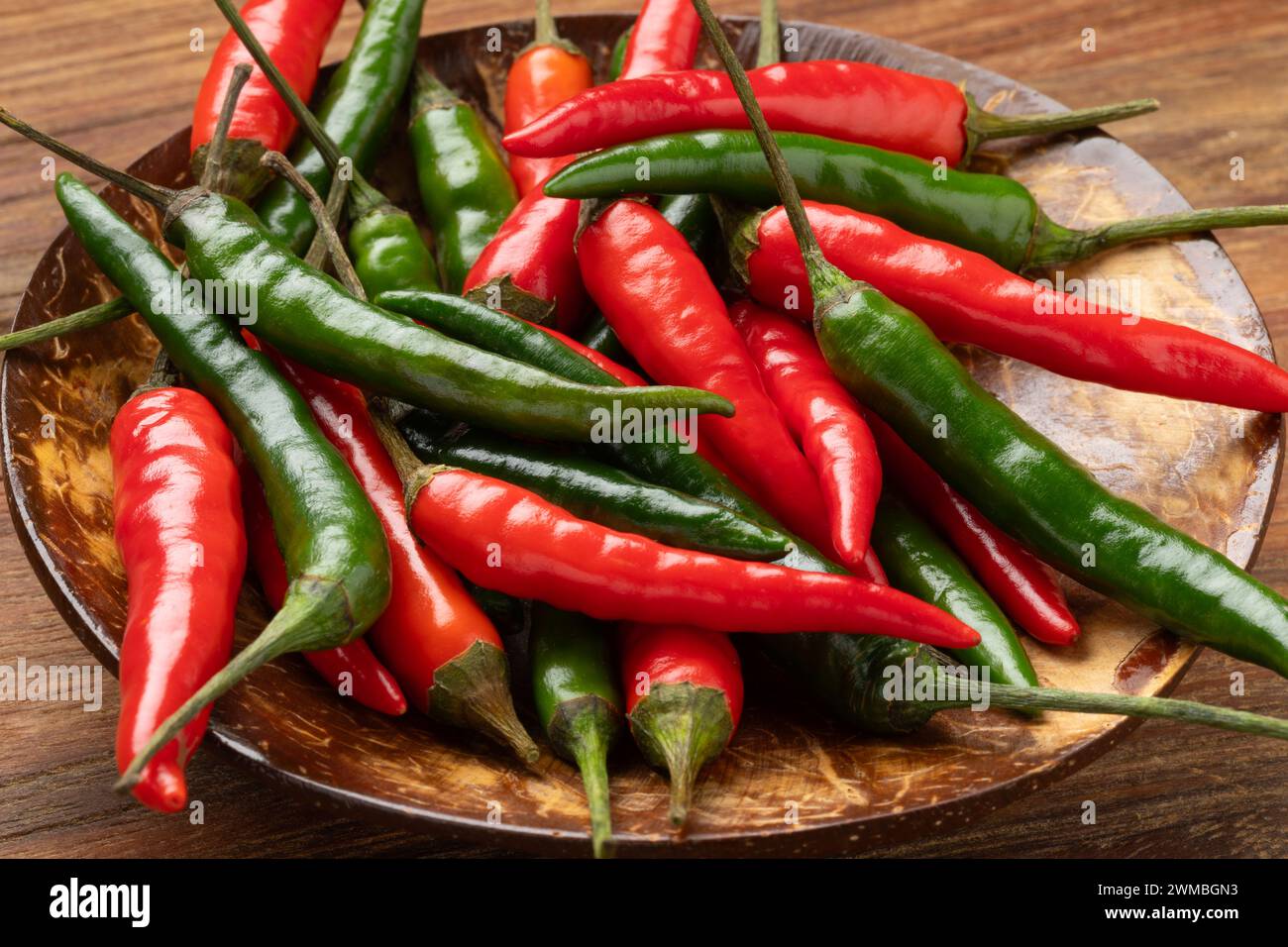 Bowl with whole fresh raw green and red rawit hot peppers close up Stock Photo