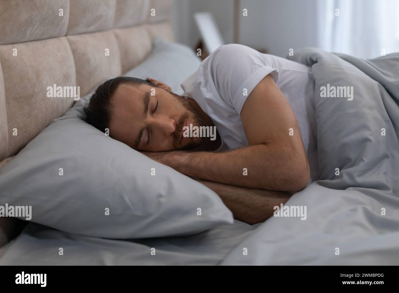 European man sleeping peacefully in cozy bed at home Stock Photo