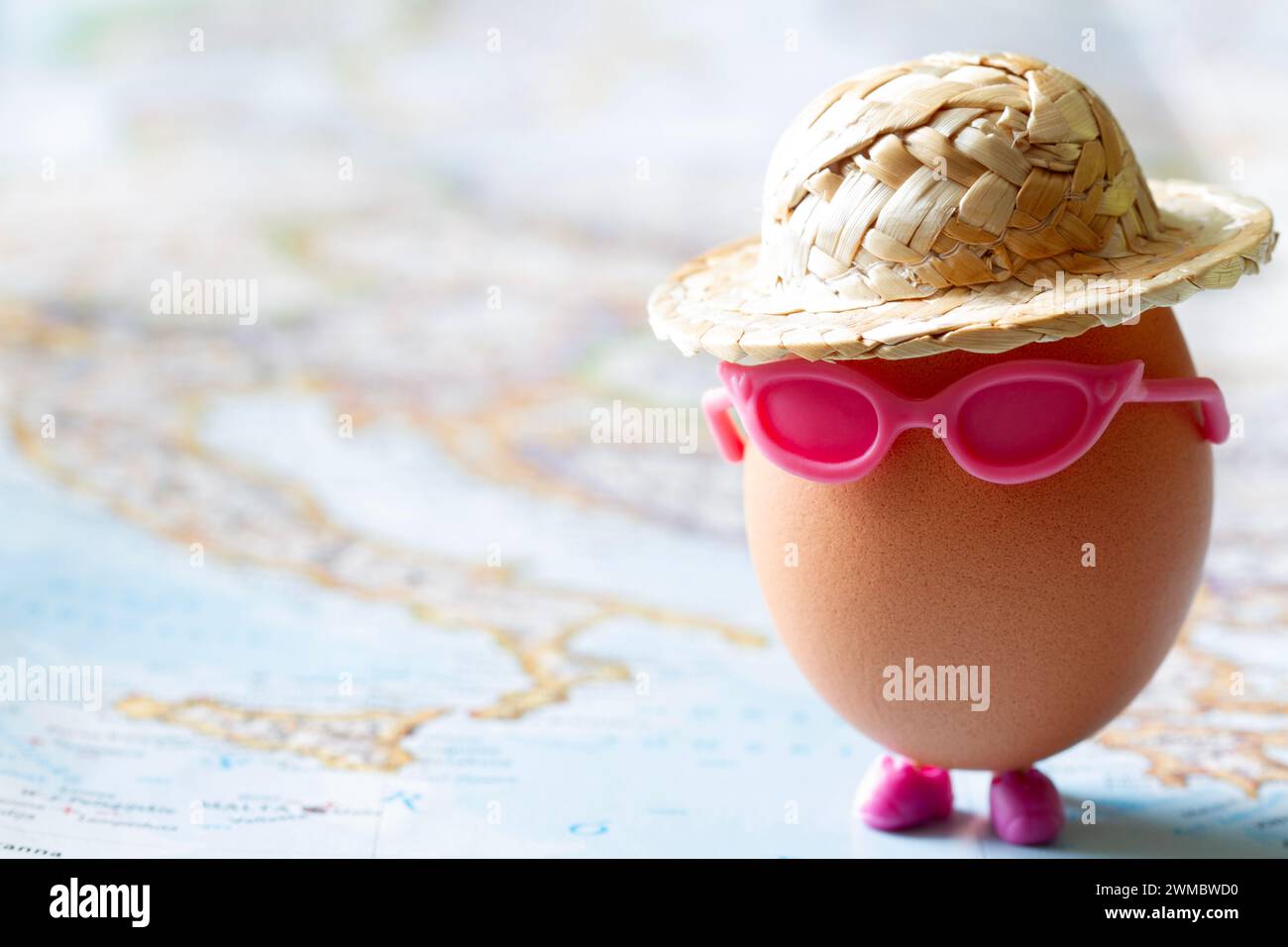 Easter egg with sunglasses in hat on map, creative easter travel concept Stock Photo