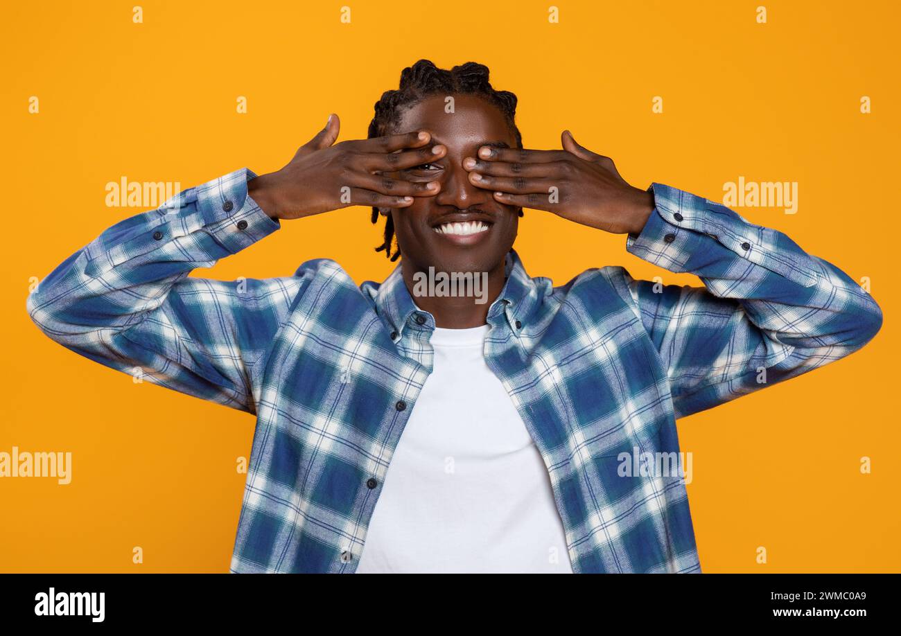 Happy young black man with braids hairstyle covering his eyes with ...