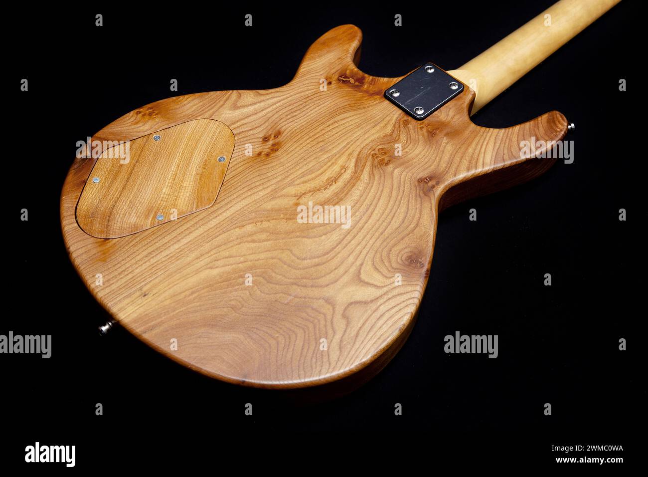 Hand built electric guitar made of elm wood. Hand made guitar. Elm tree wood, elm timber. Satin finish, control cavity cover, two piece. Stock Photo