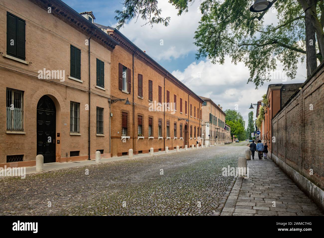 Ferrara, Emilia Romagna, Italy. A glimpse of the street of the city, Corso Ercole I d'Este. Cobblestone street, between ancient buildings. Some people Stock Photo