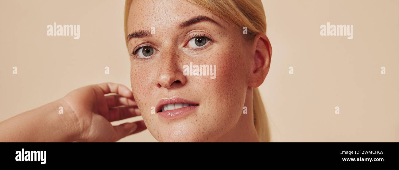 Cropped shot of a young beautiful blond woman with freckles. High-detailed portrait of a female with smooth freckled skin against a pastel backdrop. Stock Photo