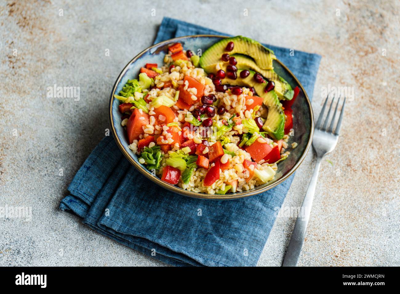 Close-up of a bulgur wheat, avocado, tomato, red pepper and pomegranate salad Stock Photo