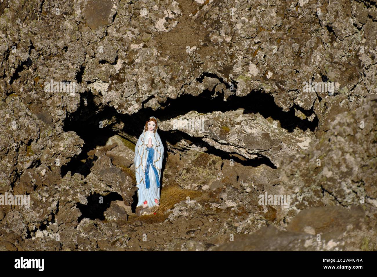 Our Lady of Lourdes statue between the lava rock in Etna Park, Sicily, Italy Stock Photo