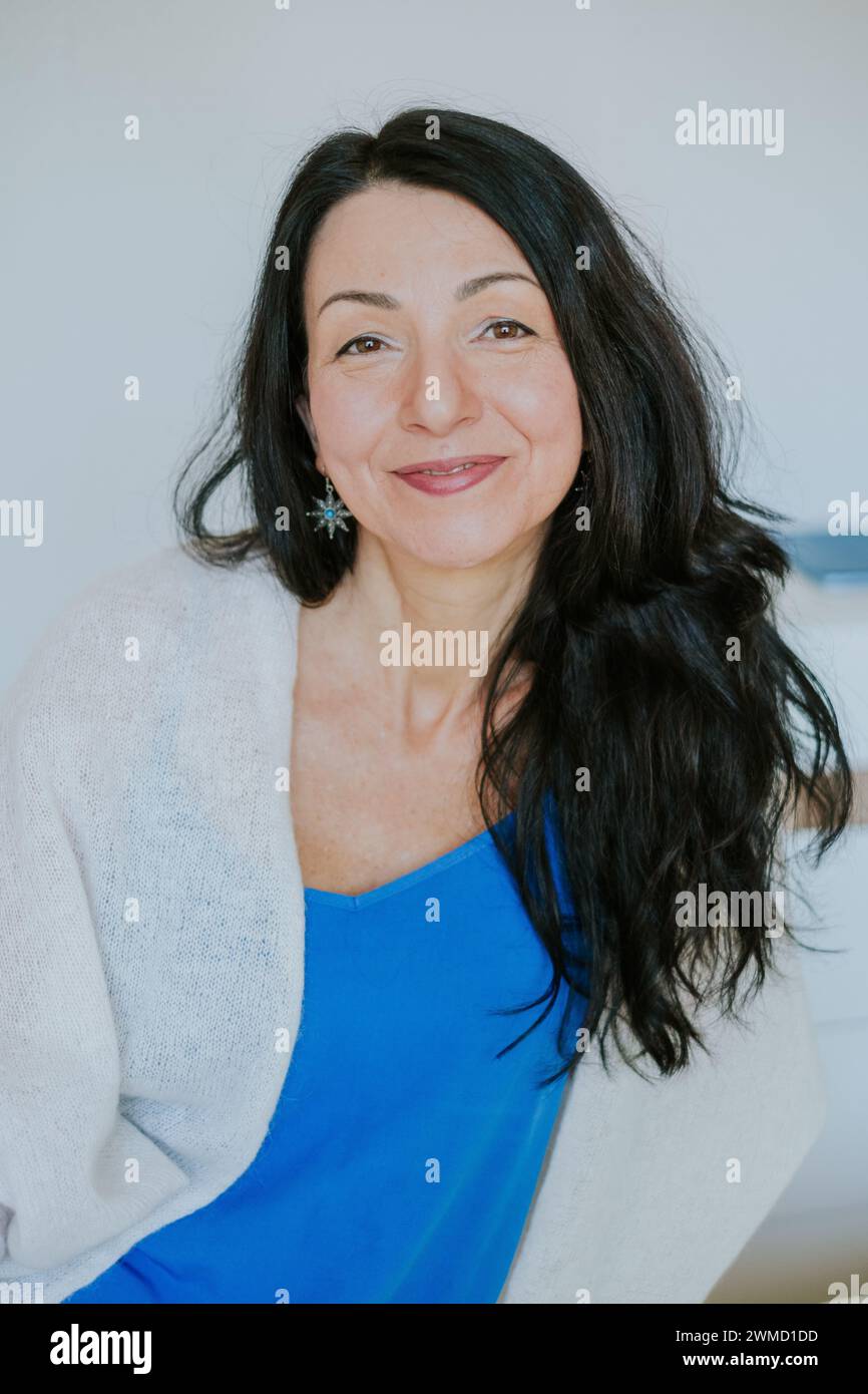 Poised woman with black hair, wearing blue, exemplifying calm during menopause's beginning. Suitable for discussions on midlife emotional health. High Stock Photo