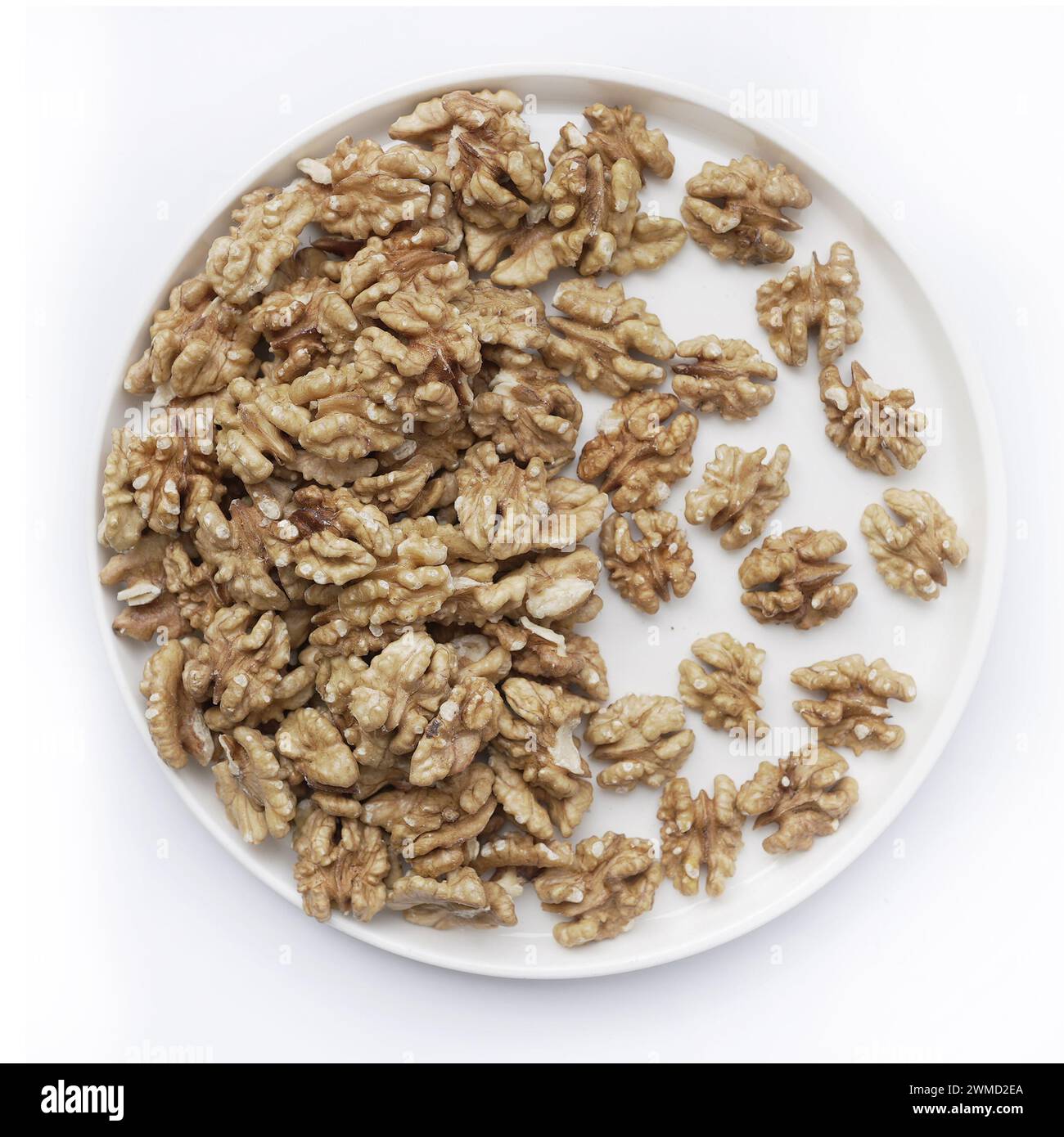 A plate brimming with walnut halves showcases the rich textures and natural oils of these nutritious nuts. Perfect for culinary use or as a healthy snack. Stock Photo