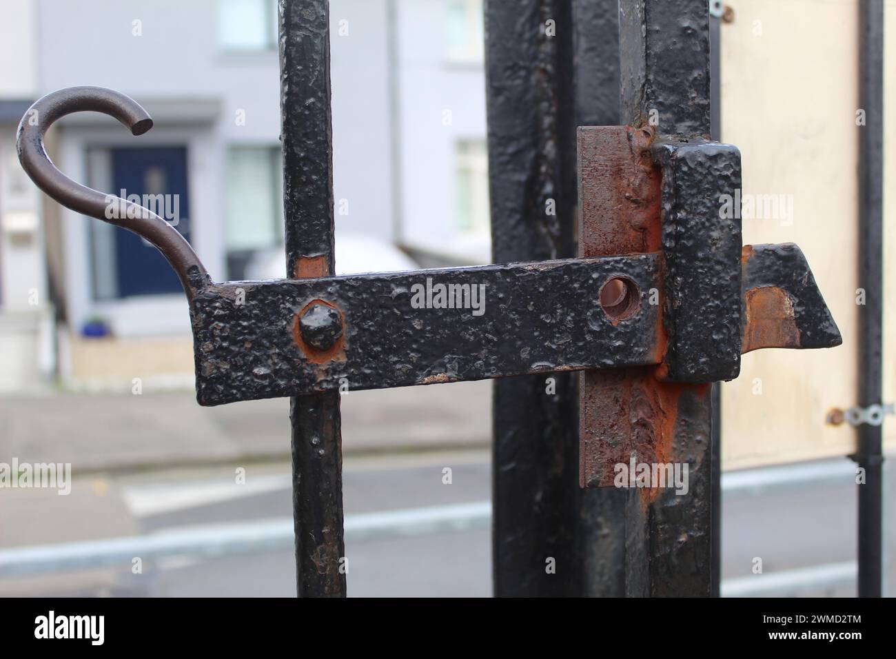 A close up photo of a black, antique and rusty gate lock beside a road. Stock Photo