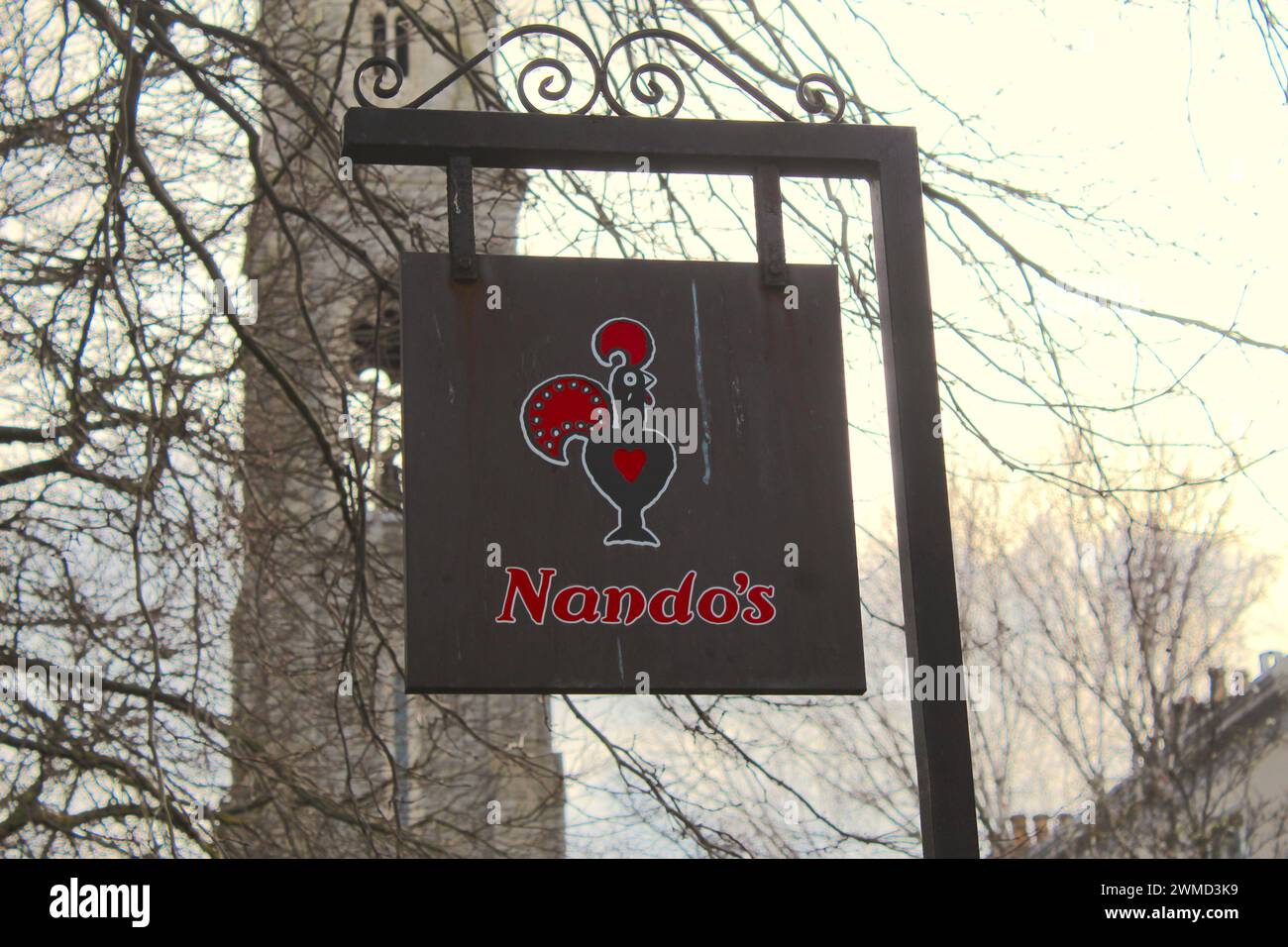 Dublin, Ireland - February 24th 2024: A photo of Nandos food chain logo hanging from a board with a orange sky in the background. Stock Photo