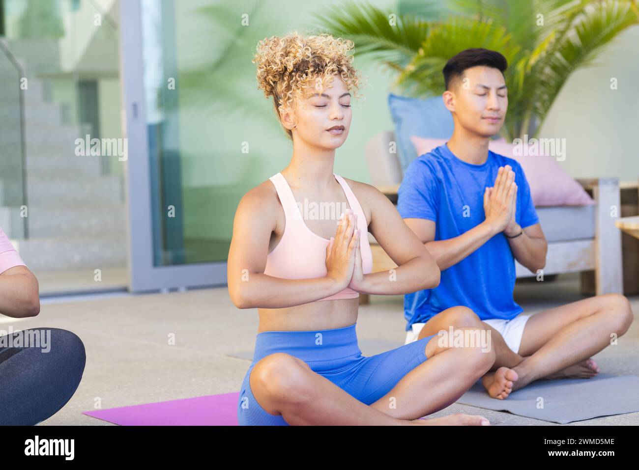 Young biracial woman and young Asian man practice yoga outdoors Stock Photo