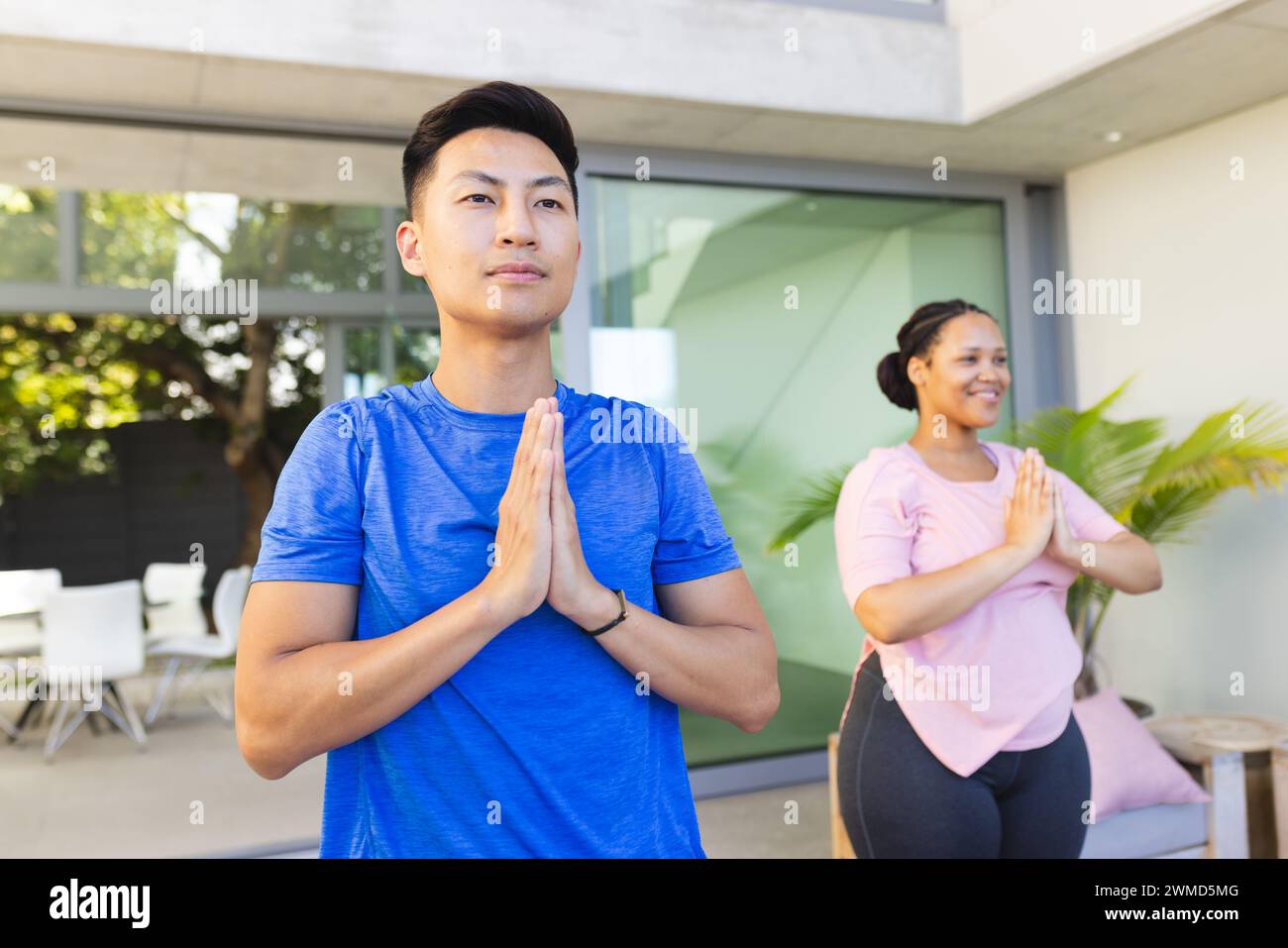 Young Asian man and biracial woman practice yoga outdoors Stock Photo