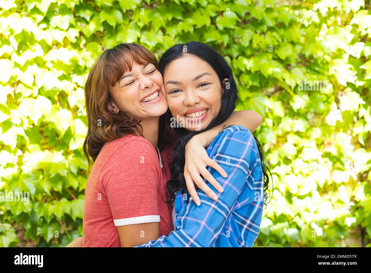 Biracial female friends share a joyful embrace outdoors Stock Photo