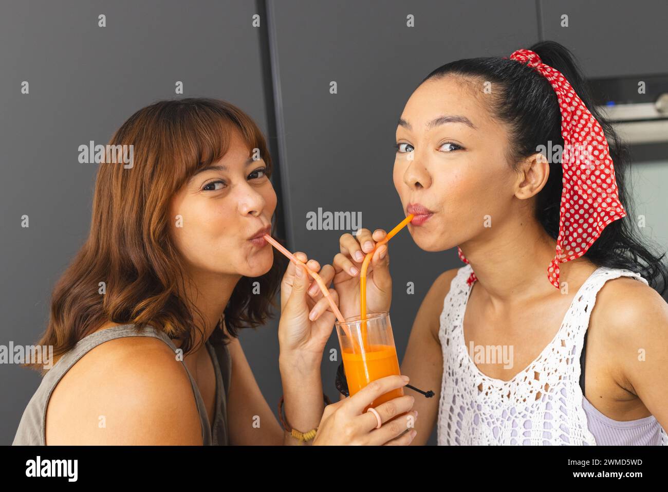 Biracial female friends enjoy a fresh juice at home Stock Photo