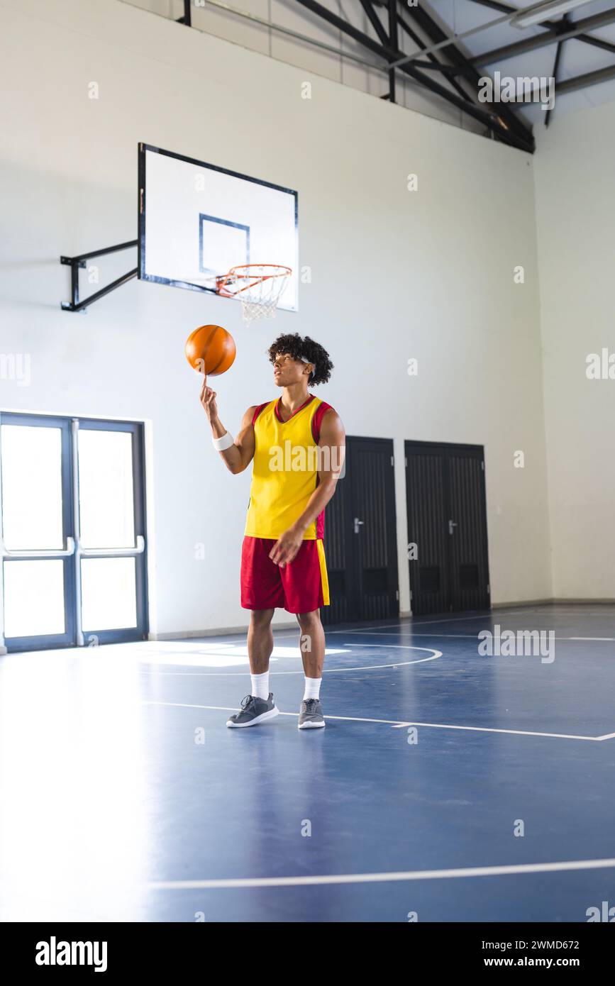 Young biracial man practices basketball in an indoor court Stock Photo