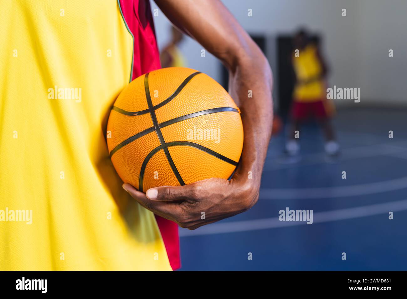 Close-up of an African American man holding a basketball in a gym Stock Photo