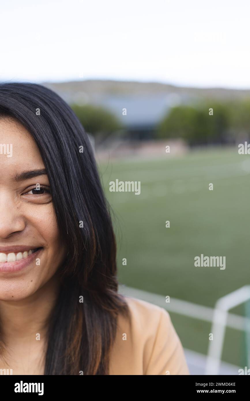 Young biracial woman smiles at an outdoor sports field Stock Photo