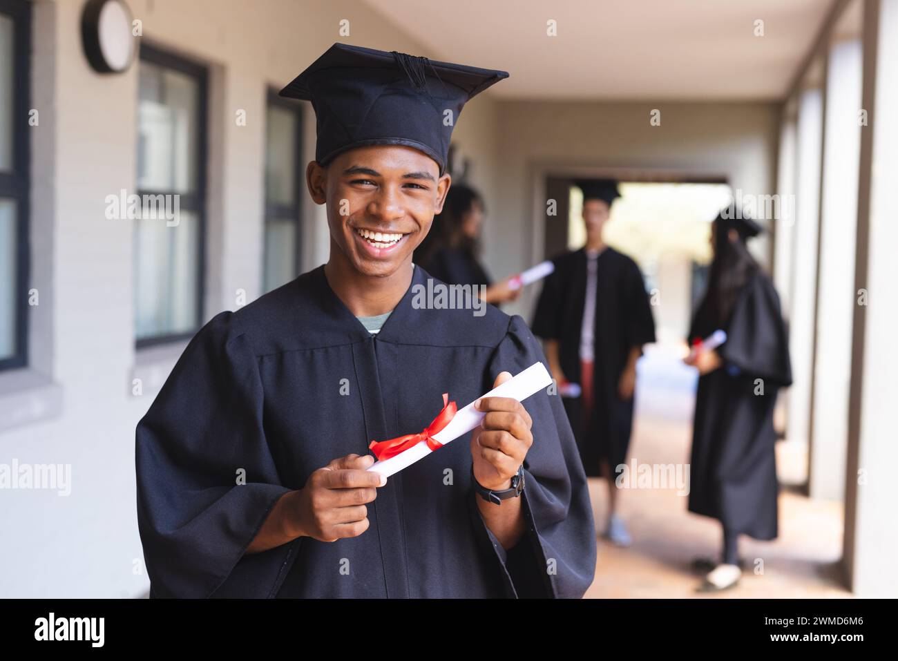 Beaming graduate holds his diploma at high school Stock Photo