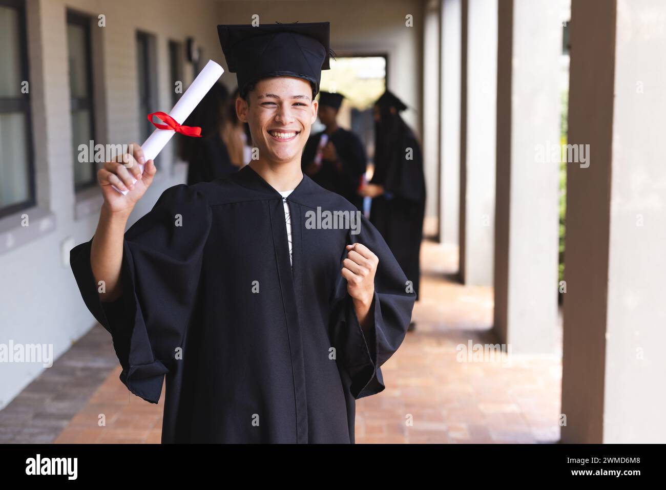 Biracial teenage boy celebrates graduation at high school Stock Photo