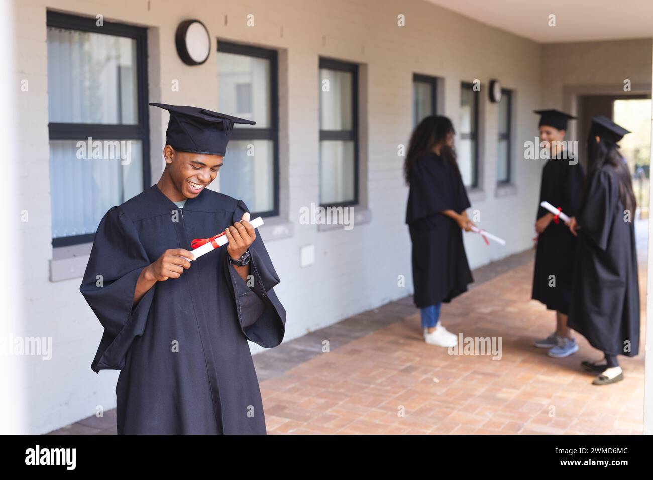 Teenage biracial boy in graduation attire at high school Stock Photo