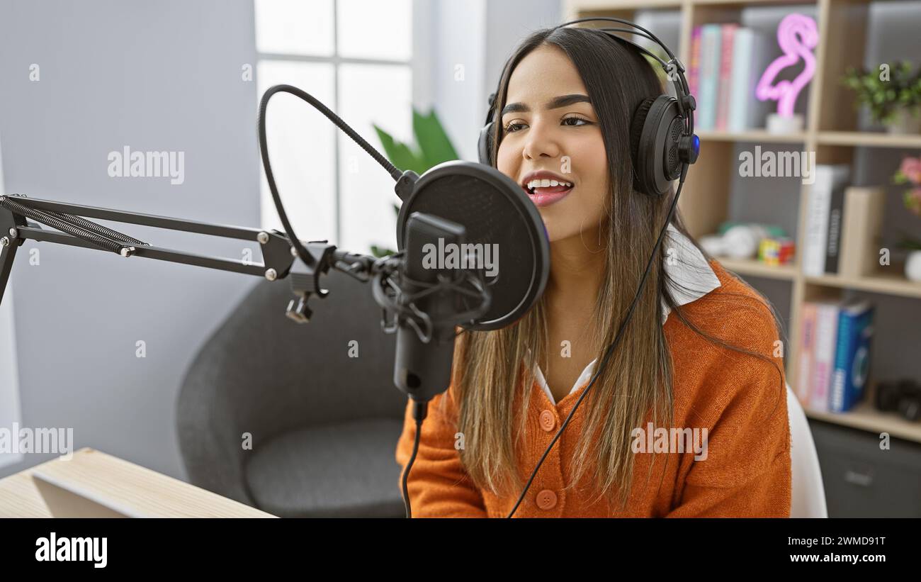 A young hispanic woman engages as a host at a radio studio, portraying an air of professionalism and charm. Stock Photo