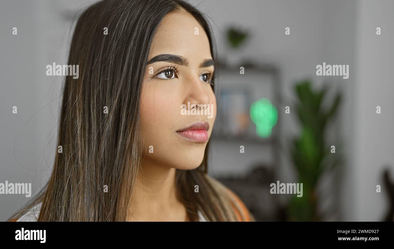 A contemplative young hispanic woman indoors with a modern living room