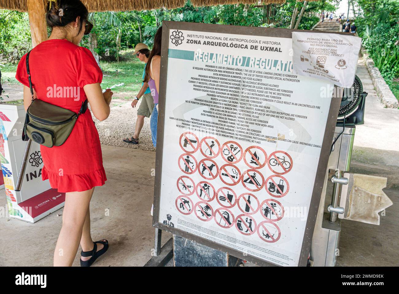 Merida Mexico,Puuc style Uxmal Archaeological Zone Site,Zona Arqueologica de Uxmal,classic Mayan city,arriving visitors,sign rules regulations,woman w Stock Photo