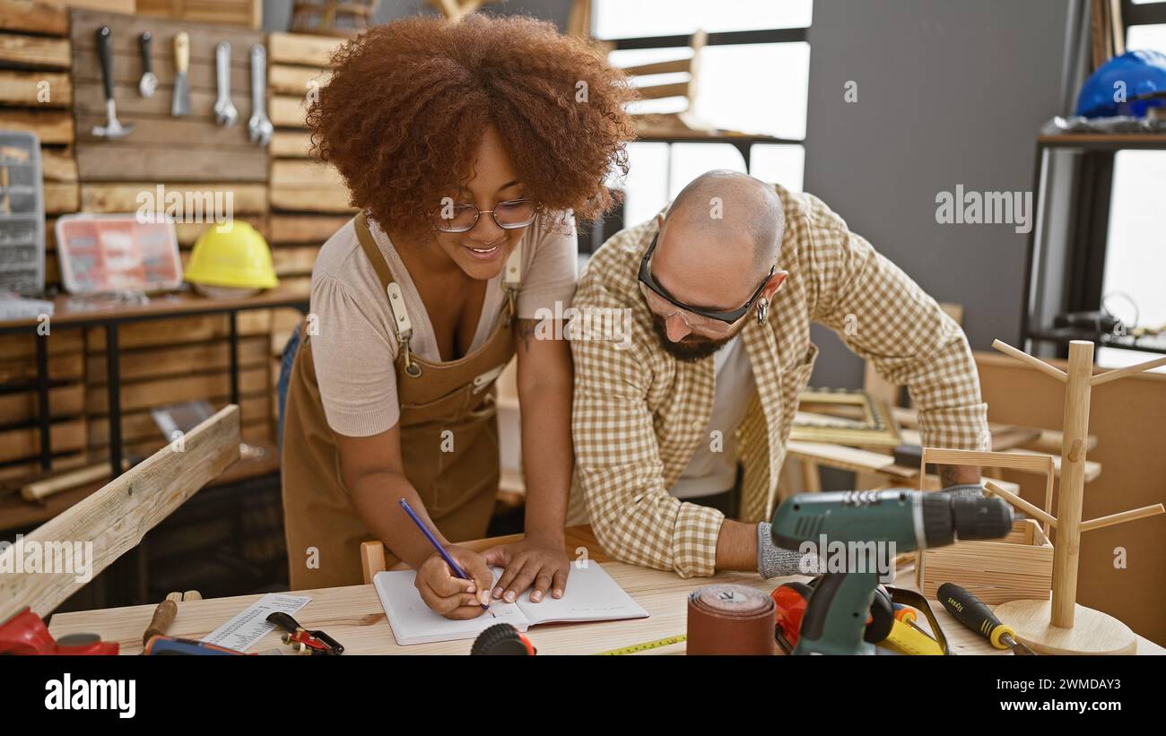 Two smiling carpenters confidently taking notes in their woodworking workshop Stock Photo