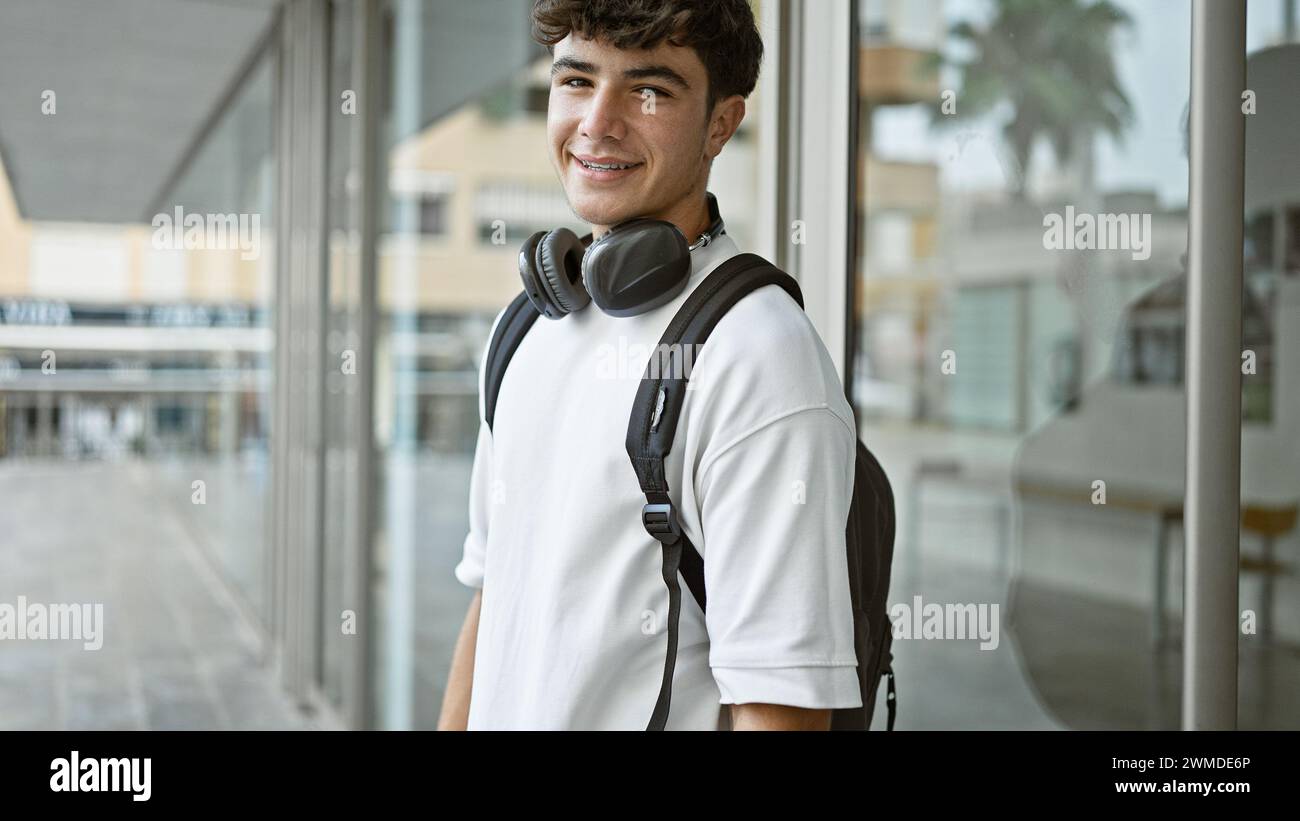 Cheerful young hispanic male student standing outdoors enjoying campus ...