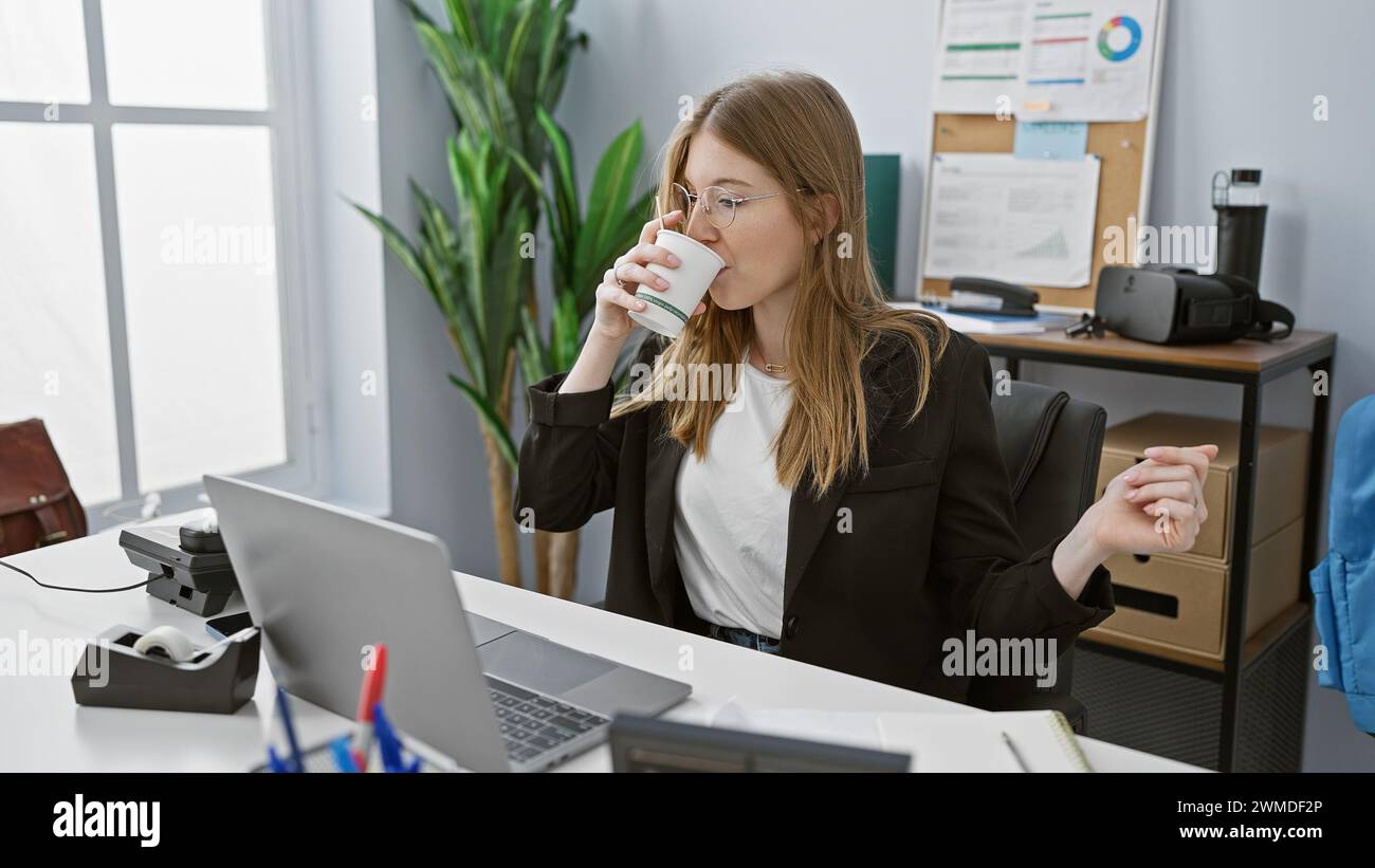 A professional young woman enjoys a coffee break at her modern office ...