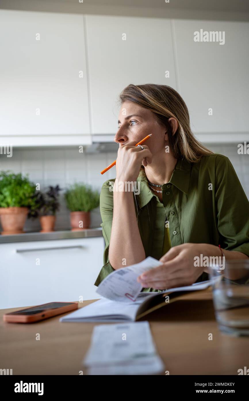 Thoughtful female analysing budget, verifying income and expenses, thinking while looking at window Stock Photo
