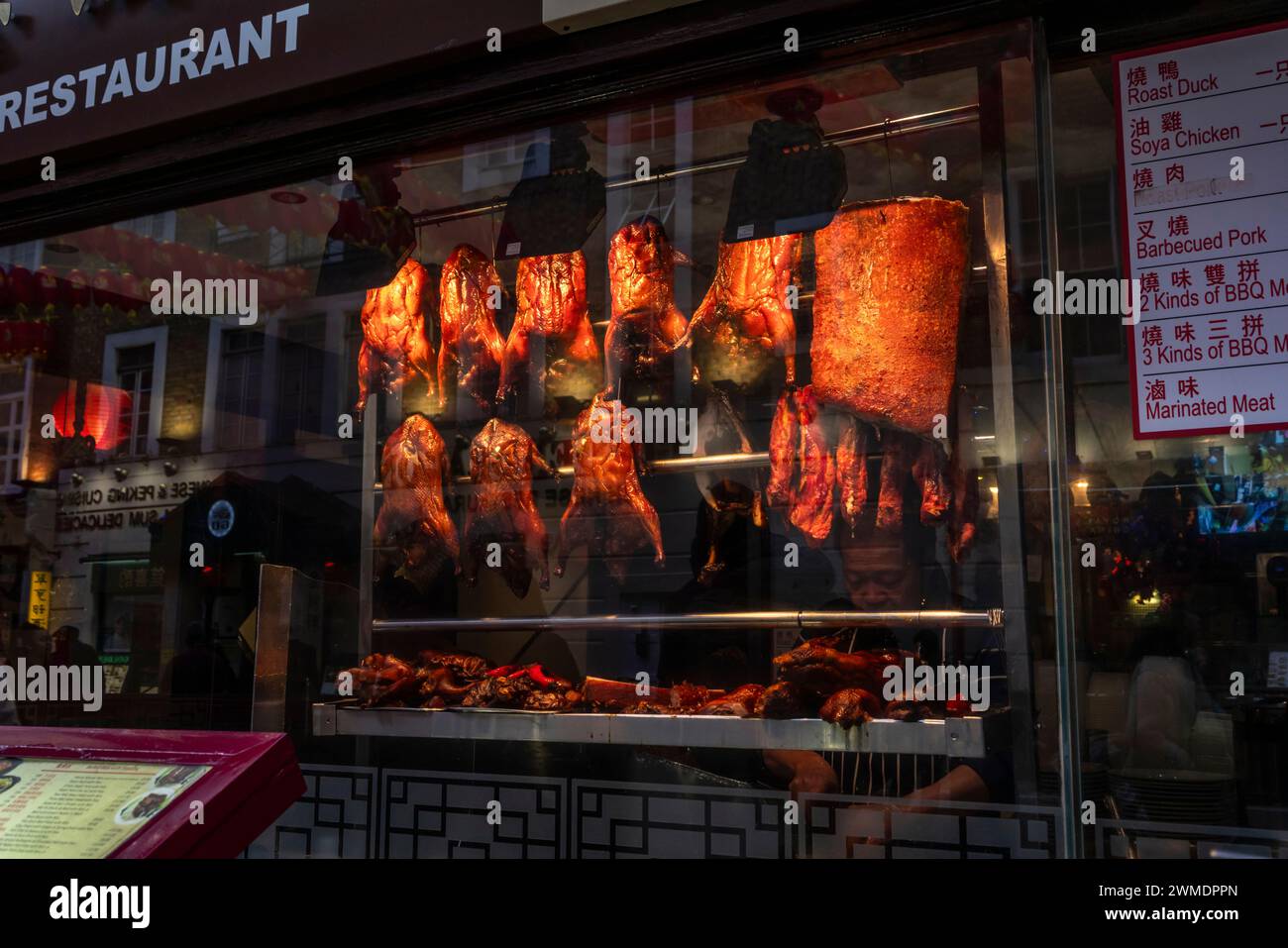 Roasted chicken and pork meat hanging on display in a Chinese restaurant window in Chinatown in Soho, London, England, UK Stock Photo