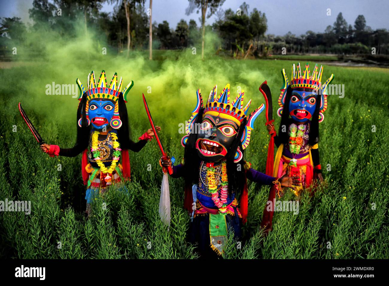 Masked dancers of Gomira dance troupe perform at a big rice field at a village near Raiganj. Gomira is a masked dance form. The word ‘Gomira' has been derived from the colloquial form of the word ‘Gram-Chandi' or the female deity who is the protective force of the village. The exact origin of the dance form is not traceable and the knowledge has been lost over time. Gomira dance is a rural dance form mainly practiced in the Dinajpur district of West Bengal. The Gomira dances are organized to appease the deity to usher in the 'good forces' and drive out the 'evil forces'. It is usually organise Stock Photo