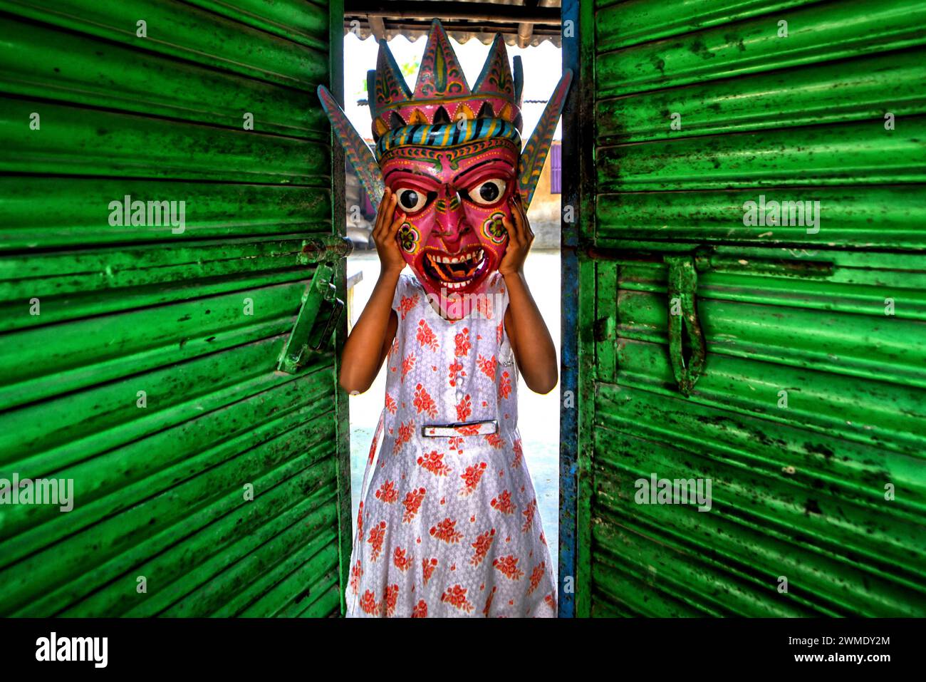 A child seen posing with a Dragon Mask at Kushmandi village near Raiganj. Gomira is a masked dance form. The word ‘Gomira' has been derived from the colloquial form of the word ‘Gram-Chandi' or the female deity who is the protective force of the village. The exact origin of the dance form is not traceable and the knowledge has been lost over time. Gomira dance is a rural dance form mainly practiced in the Dinajpur district of West Bengal. The Gomira dances are organized to appease the deity to usher in the 'good forces' and drive out the 'evil forces'. It is usually organised during mid-Februa Stock Photo