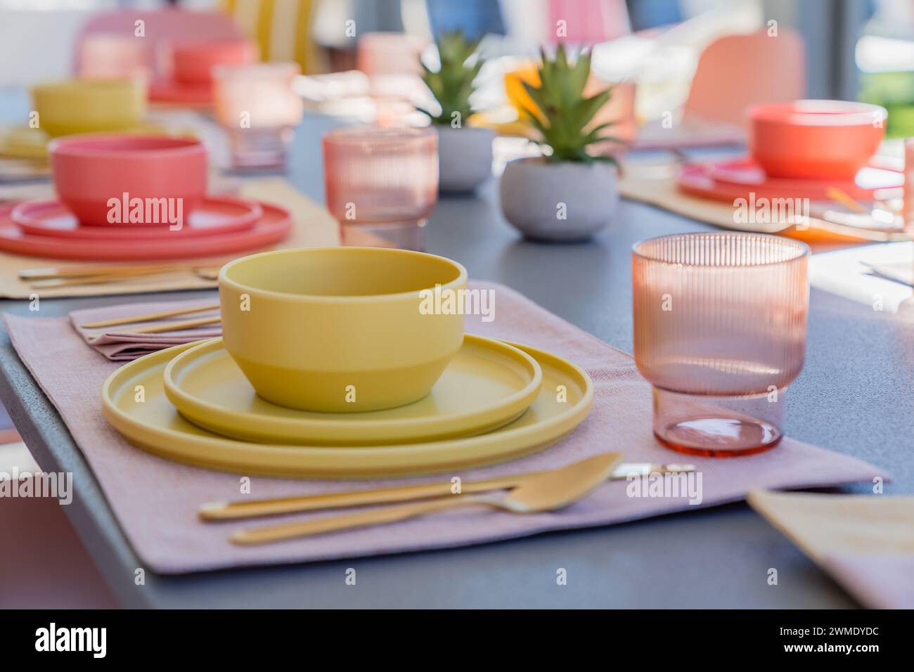 Close-up of a set dining table with bowls, plates, glasses, and silverware outdoors Stock Photo