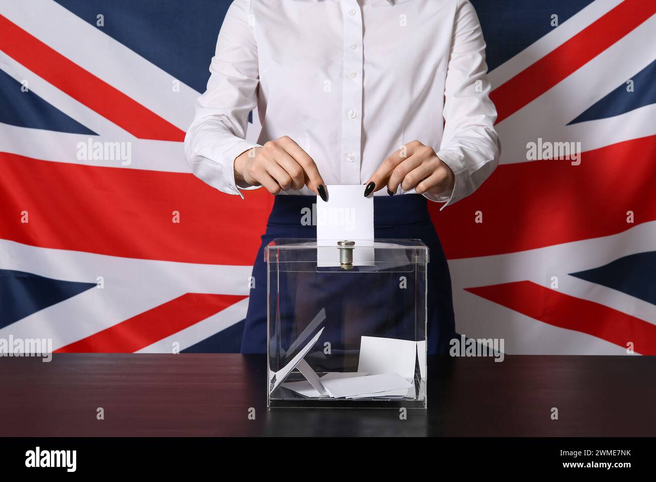 Voting young woman near ballot box against UK flag, closeup Stock Photo