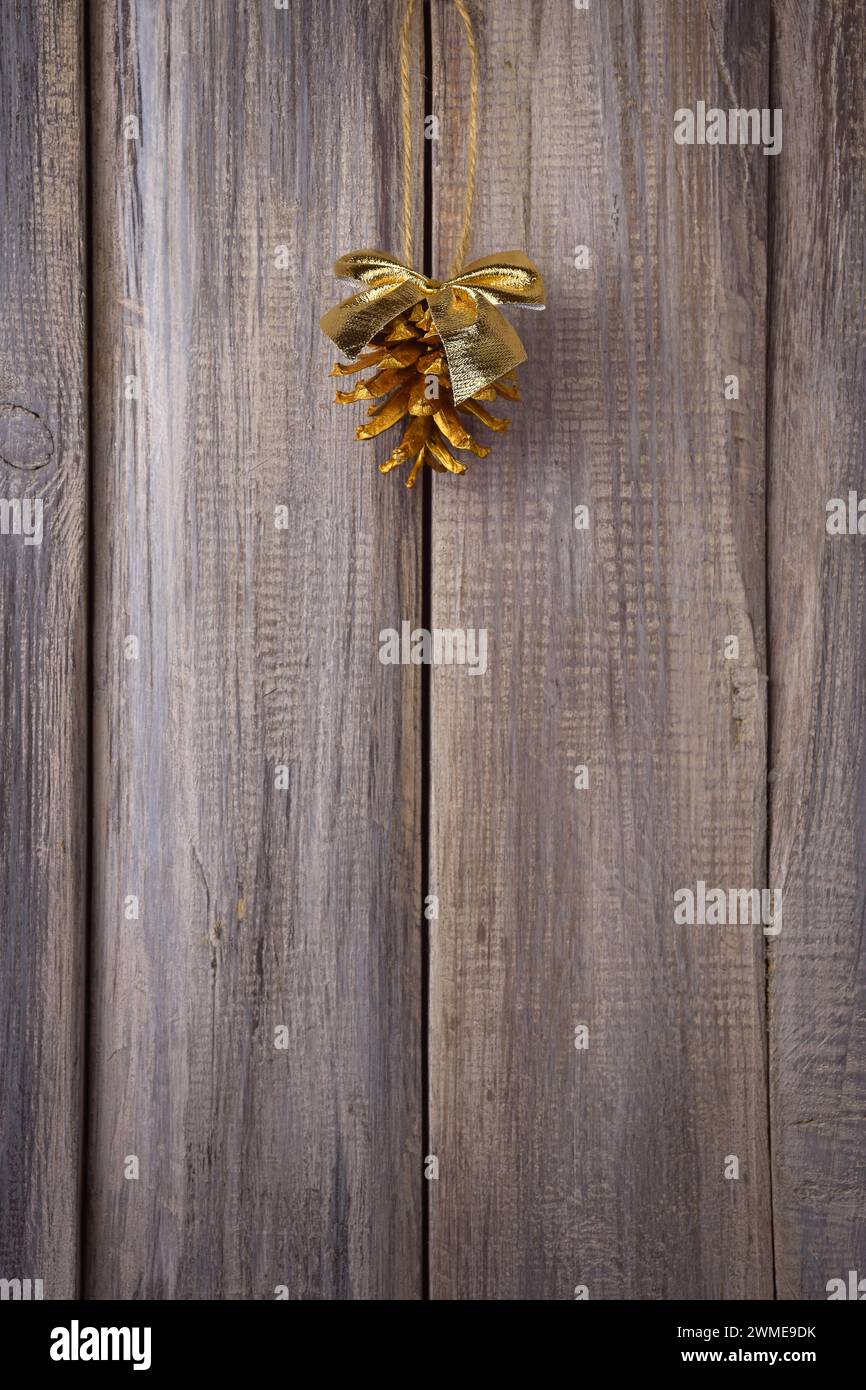 Festive decor. Golden pine cones on an old wooden door. Comfort and tradition. Christmas atmosphere. Cute trinkets. Stock Photo