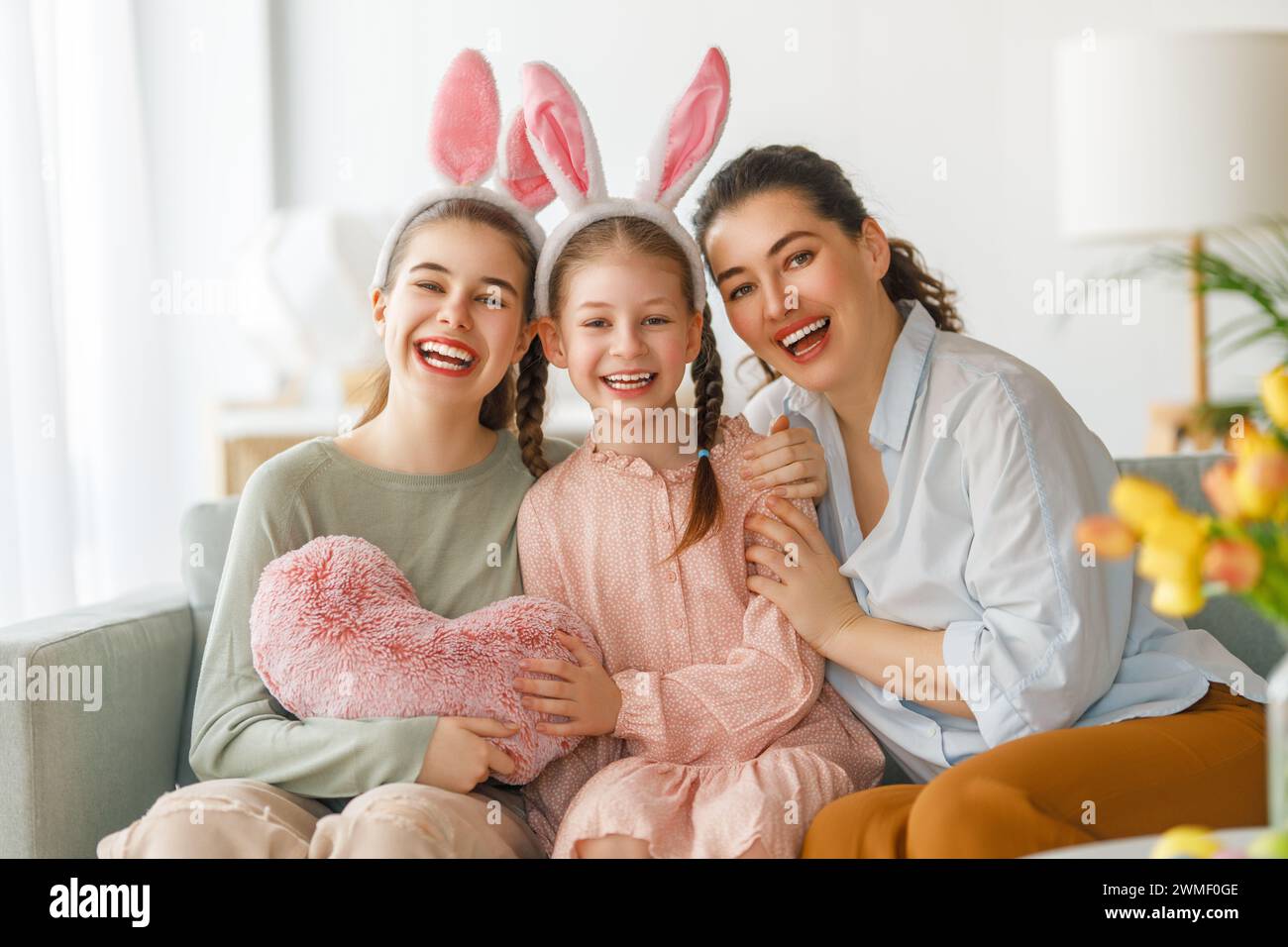 Happy holiday. Mother and her daughters. Family celebrating Easter. Cute little children girls are wearing bunny ears. Stock Photo