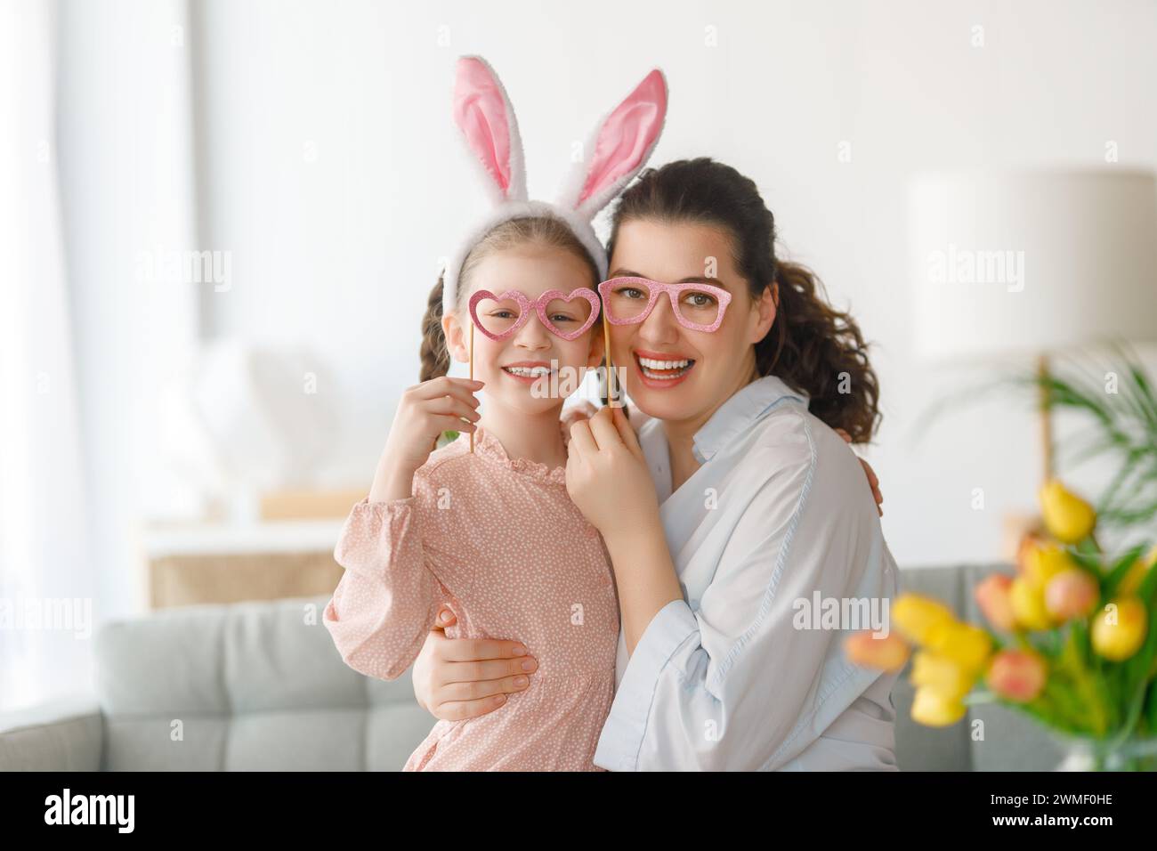 Happy holiday. Mother and her daughter. Family celebrating Easter. Cute little child girl is wearing bunny ears. Stock Photo