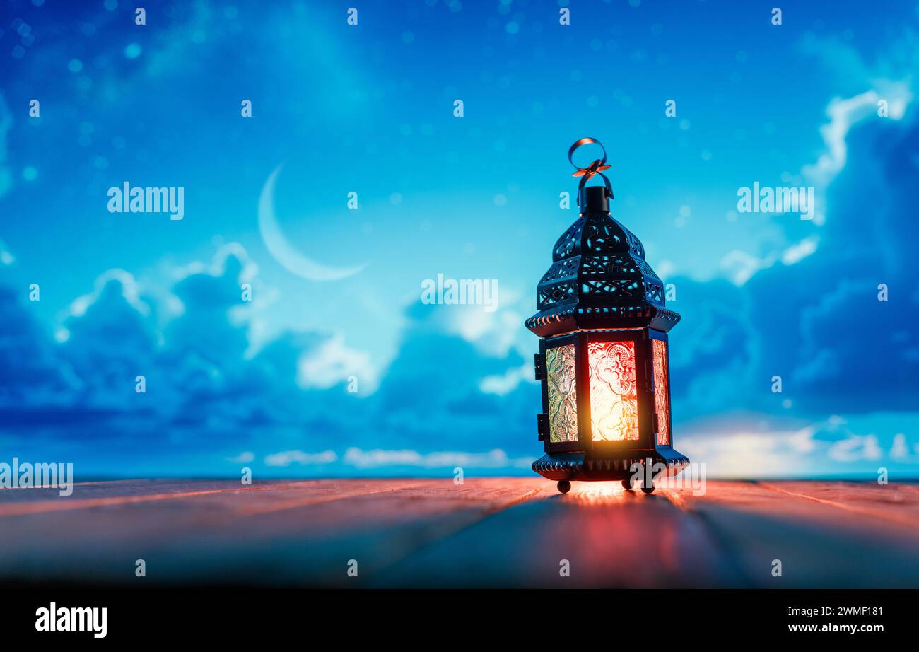 Ornamental Arabic lantern with burning candle glowing at night. Festive greeting card, invitation for Muslim holy month Ramadan Kareem. Stock Photo