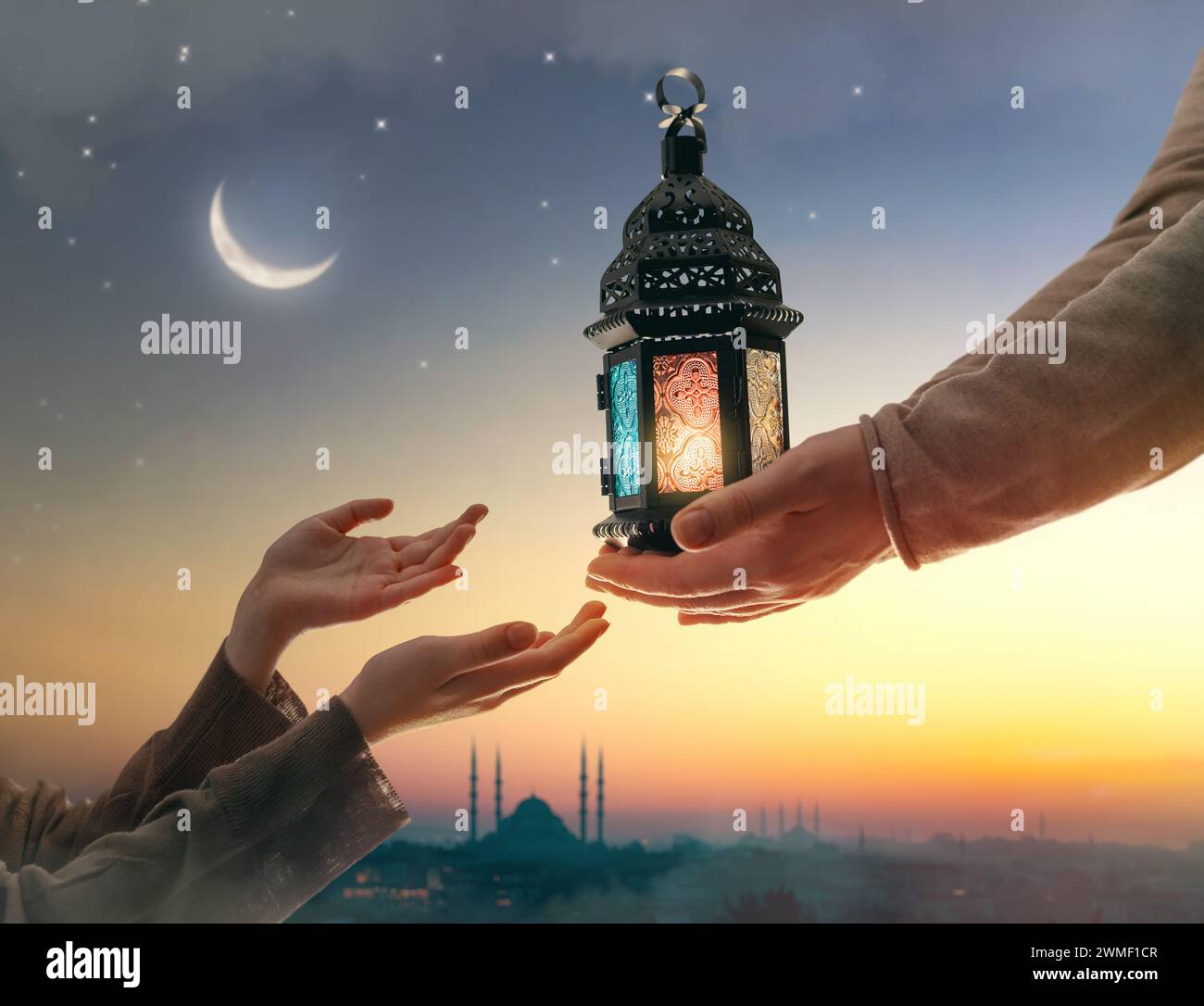 Ornamental Arabic lantern with burning candle glowing in hand. Festive greeting card, invitation for Muslim holy month Ramadan Kareem. Stock Photo