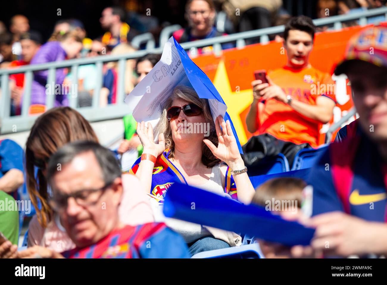 FANS, BARCELONA FC, 2015: A female fan improvises protection against the strong evening sunshine. Fans gather at Camp Nou before match. The final game of the La Liga 2014-15 season in Spain between Barcelona FC and Deportivo de La Coruna at Camp Nou, Barcelona on May 23 2015. The Game finished 2-2. Barcelona celebrated winning the championship title and legend Xavi's final home game. Deportiva got the point they needed to avoid relegation. Photograph: Rob Watkins Stock Photo