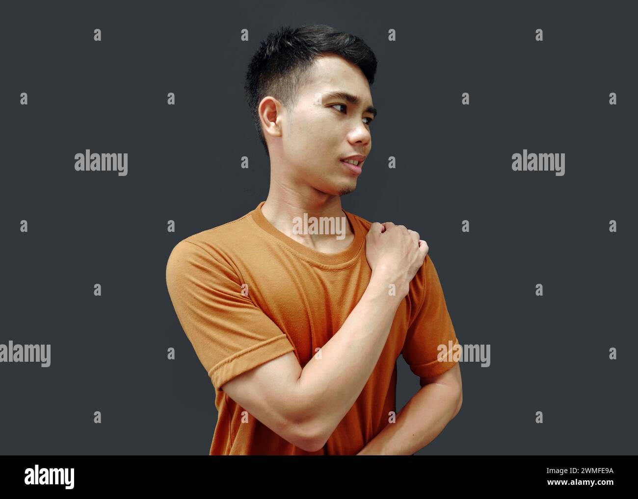 Man massaging stiff shoulders, tired sad man rubbing tense muscles to relieve joint shoulder pain, isolated on blank background. Concept of central ne Stock Photo