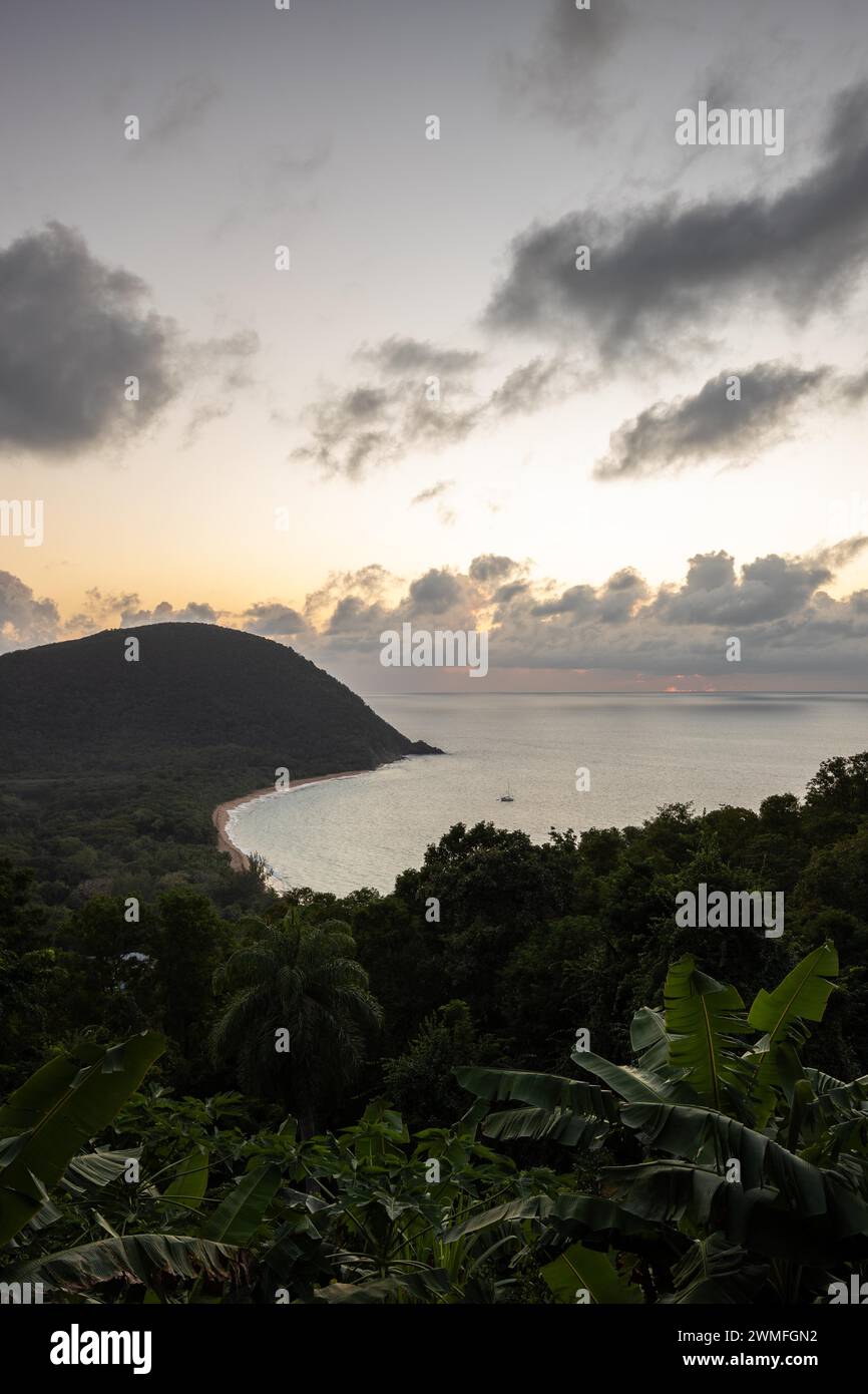 View from a mountain onto an empty sandy beach, the turquoise-coloured sea and the surrounding landscape. The evening sun illuminates the natural Stock Photo